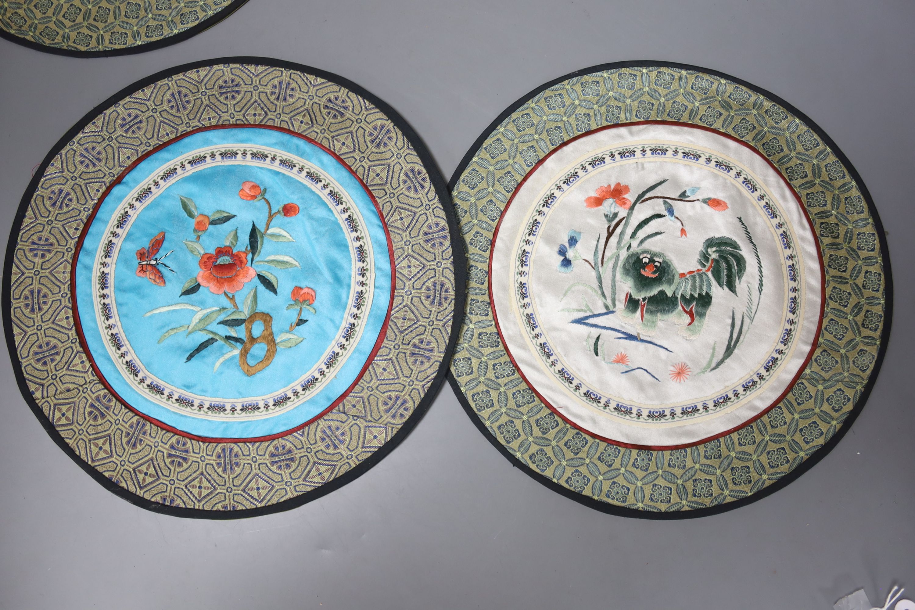 A Chinese porcelain brush pot, various embroidered silk mats etc.
